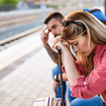 Meaningful Travel: Exhausted couple waiting for a train with luggage.