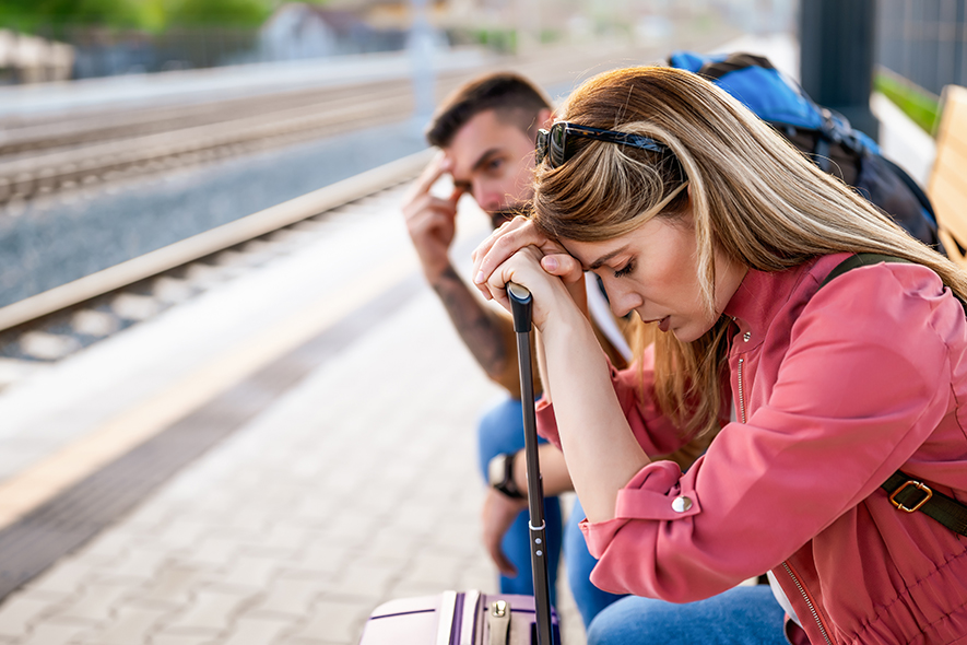 Meaningful Travel: Exhausted couple waiting for a train with luggage.